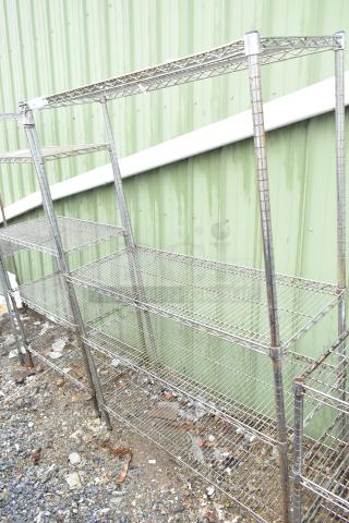 Chrome finish 4-tier wire shelving unit, evident signs of wear, buyer must dismantle, located outdoors on gravel.