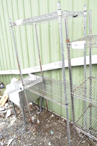 Chrome finish 3-tier wire shelving unit outdoors, slightly rusted. Note: Buyer must dismantle for shipping.