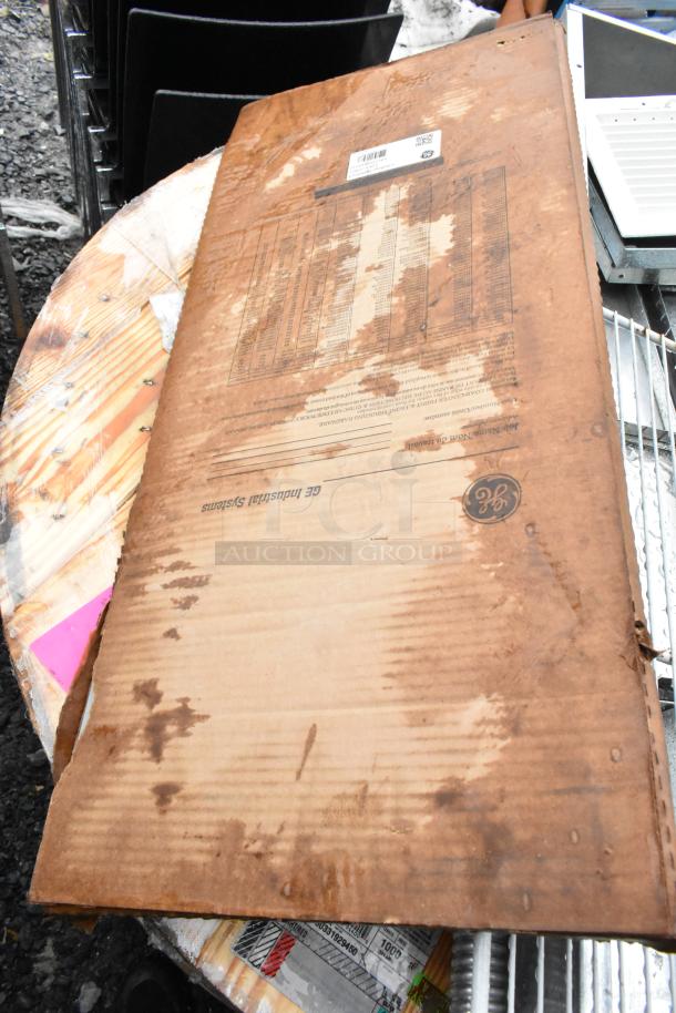 Cardboard box with visible GE Industrial Systems labeling, showing signs of wear and water damage.