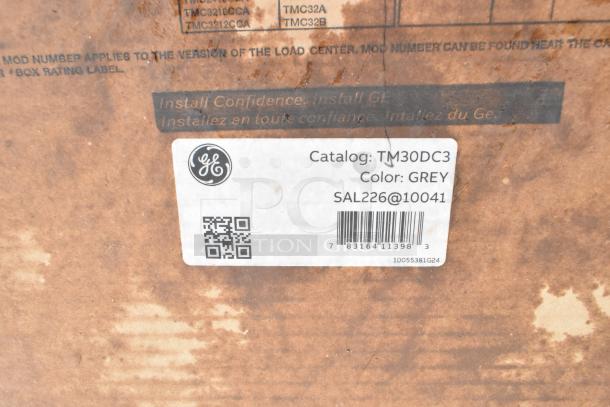 GE TM30DC3 catalog label on a rusted metal surface, details grey color, barcode, and QR code.
