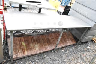 Commercial table with mounted can opener and an under shelf. Signs of wear; rust evident on the lower shelf.