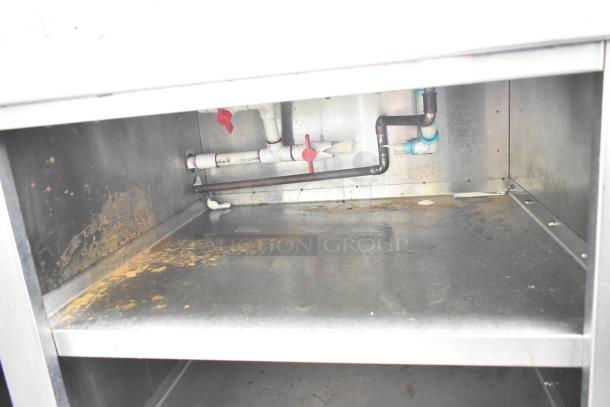 Commercial soda station underside showing internal plumbing, shelf, and signs of rust.