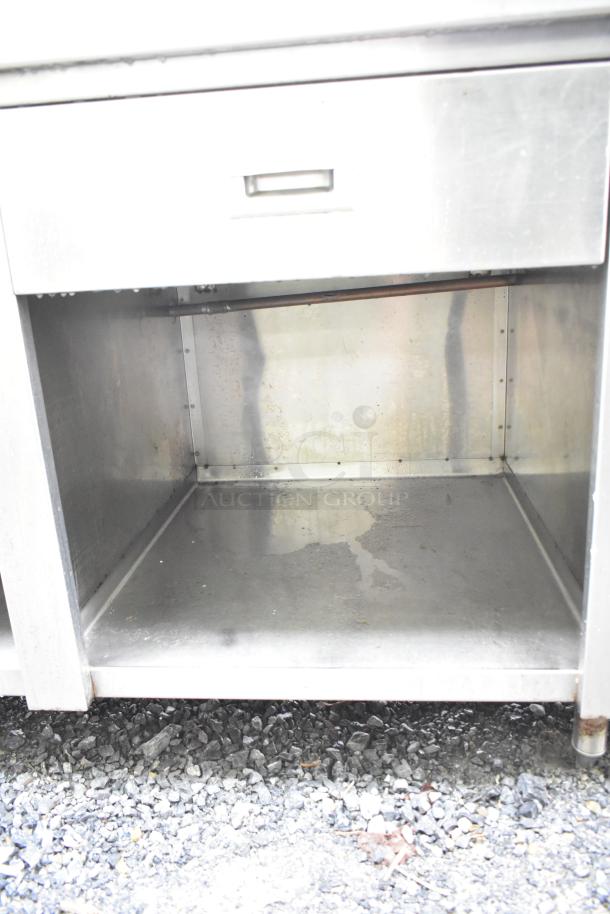 Commercial soda station with water dispenser, sink basin, drawer, and under shelves in stainless steel. Visible drawer and shelving.
