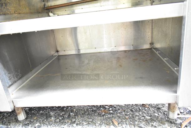 Commercial soda station with water dispenser, visible under shelves, metal construction, shows signs of wear.
