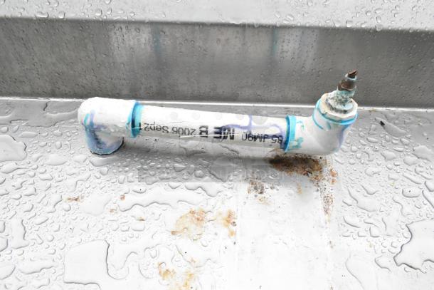 Commercial soda station with a water dispenser, sink basin, drawer, and under shelves, showing pipe detail with markings.