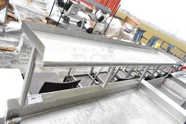 Commercial stainless steel table with over shelf and under shelves, in used condition. Auction tag reads "299."