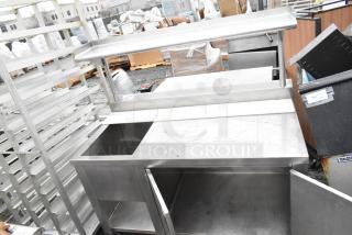 Stainless steel commercial table with bay, over shelf, doors, and undershelf. Visible wear; no markings or labels shown.