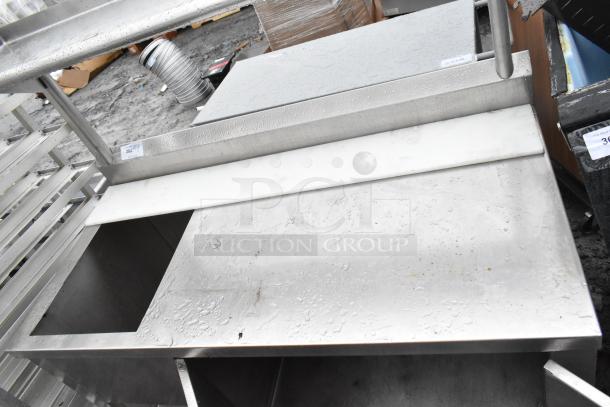 Commercial stainless steel table with bay, over shelf, doors, and undershelf. Used condition with visible wear. Lot number 302 displayed.
