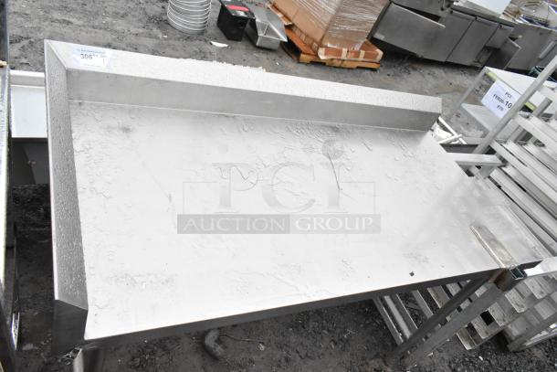 Stainless steel commercial table with mounted can opener bracket, showing some surface wear, ideal for heavy-duty kitchen use.