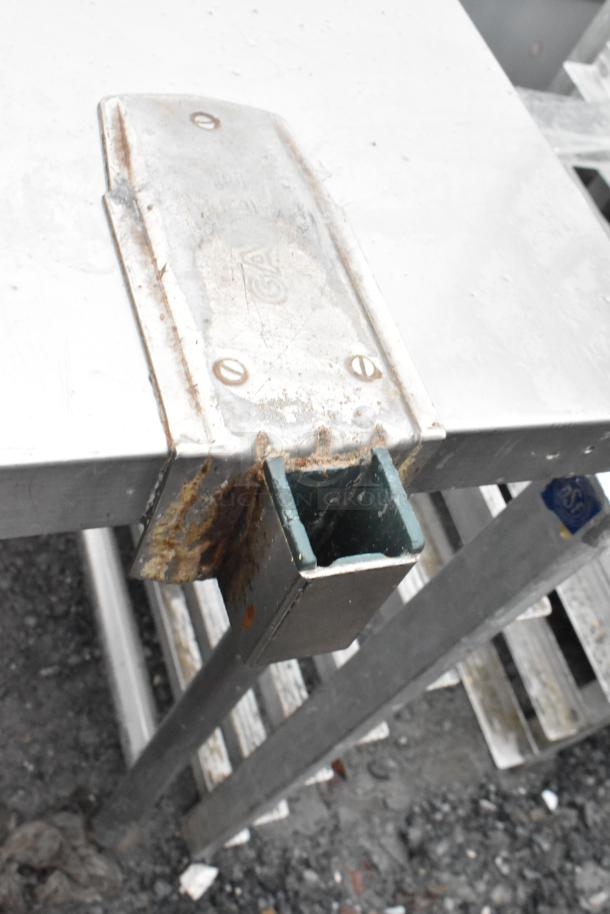 Commercial table with mounted can opener, metal construction, rust visible, sturdy condition for kitchen use.