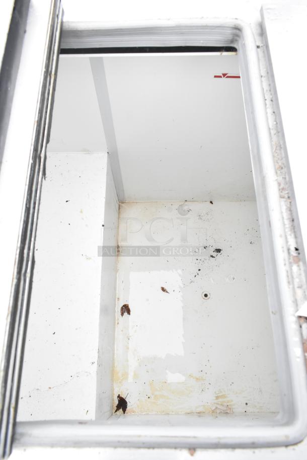 Excellence HFF-8-HC commercial chest freezer interior, showing wear and debris. Equipped with 2 center hinge lids, 115V, 1 Phase.