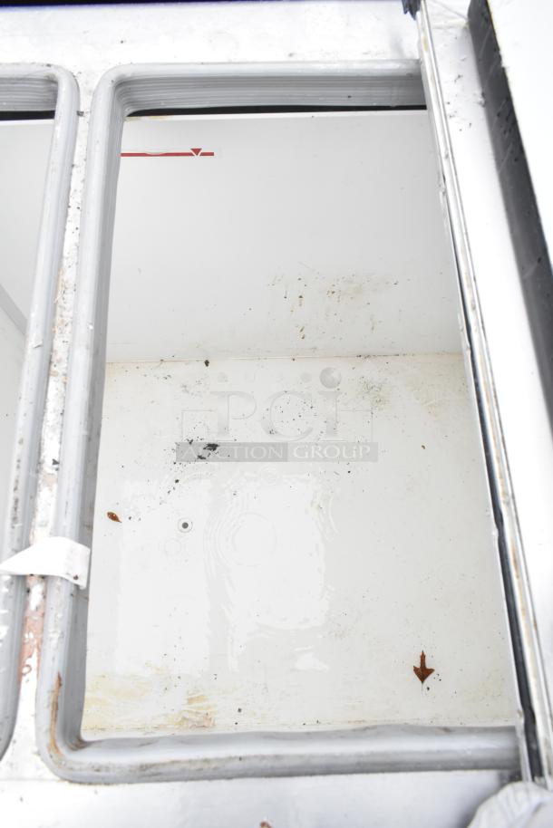 Excellence HFF-8-HC chest freezer interior, showing dual center hinge lids, visible wear, and debris on white surface.