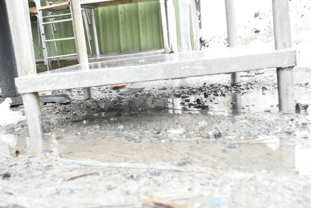 Commercial table with metal under shelf, outdoor setting, sturdy legs, fair condition, ideal for kitchen or workshop use.