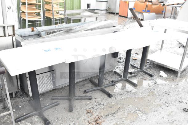 Five dining-height tables on sturdy metal bases, outdoor setting. Tables appear in used condition, ideal for commercial use.