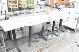 Five dining-height tables on sturdy metal bases, outdoor setting. Tables appear in used condition, ideal for commercial use.