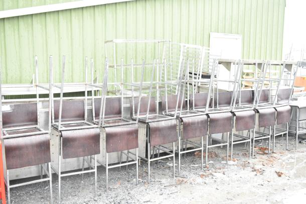 19 bar height chairs with wooden seats on chrome frames, arranged upside down outdoors. Slight wear visible.