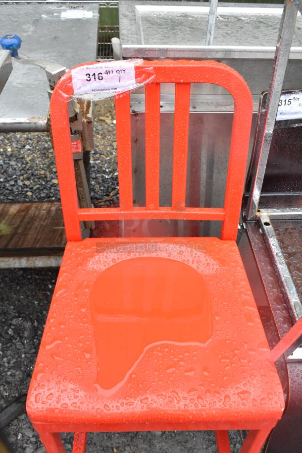 Red metal bar height chair with vertical slat back, glossy finish, and visible auction tag. Condition: Wet surface from rain.
