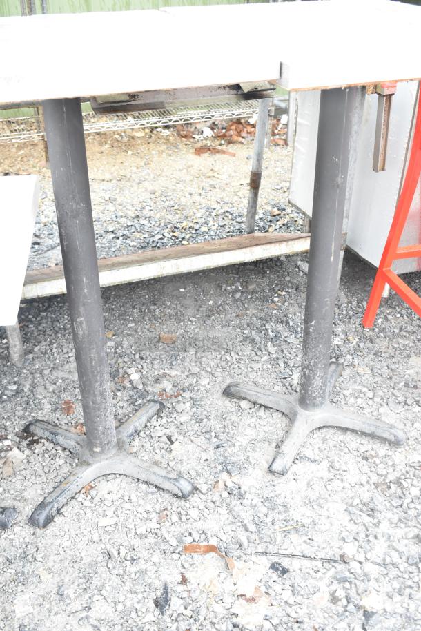 2 bar height tables with black bases, used condition, outdoor setting. No visible tags or markings.