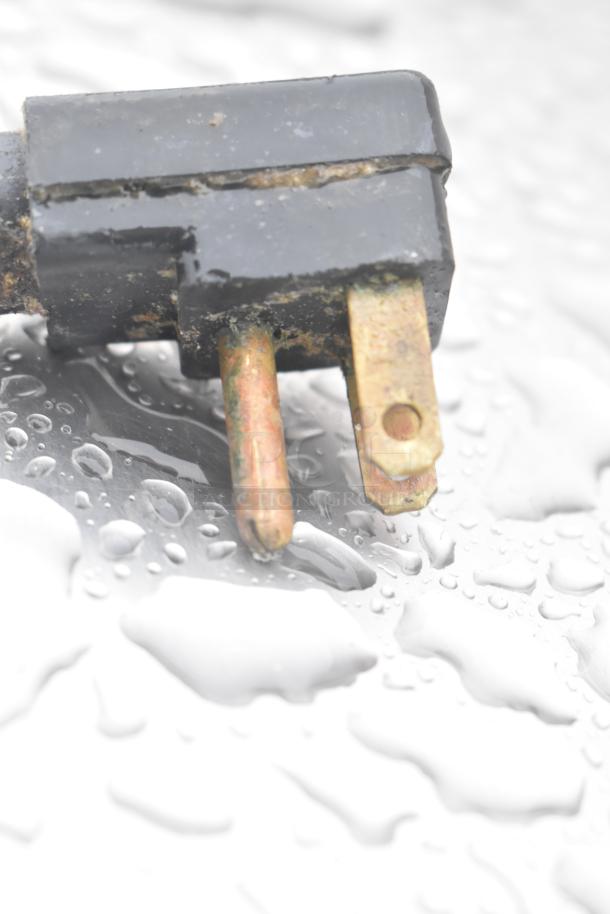 Close-up of a weathered electrical plug, showing signs of rust and moisture exposure, likely indicating use in wet conditions.