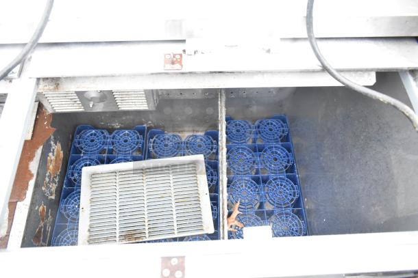 Perlick 7260E-SIL-UL bottle cooler, interior view with sliding lids open, showing wire racks and fan components. Some rust visible.