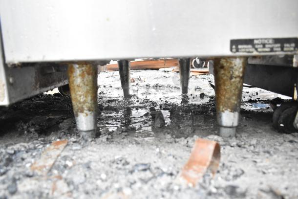 Frymaster GF14SD natural gas fryer base, showing rusted legs on uneven, wet ground. Model and notice label visible.