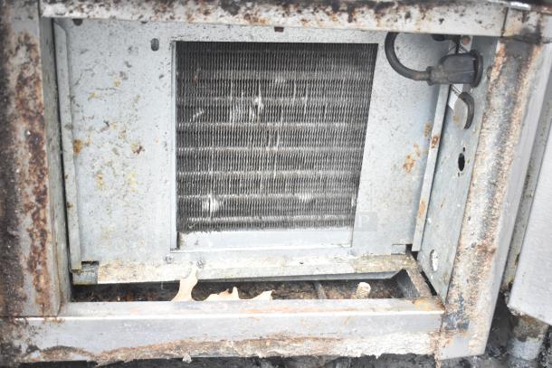Alt text: "Continental CRA68 Commercial 3 Door Undercounter Cooler, visible internal components, shows rust and wear."
