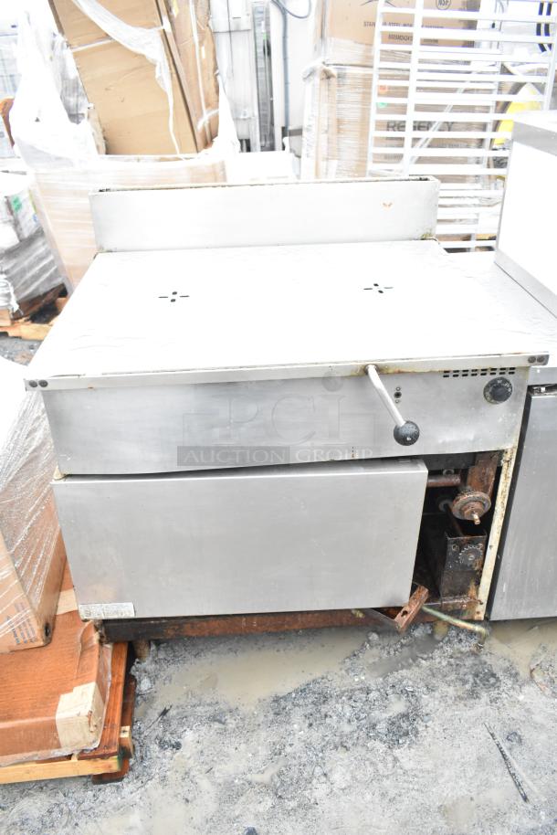 Commercial floor-style braising pan in used condition. Features a stainless steel exterior, manual controls, and visible wear.