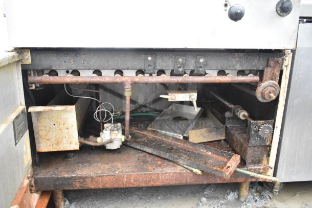 Commercial floor-style braising pan with visible rust and worn components, showing interior mechanics and piping.