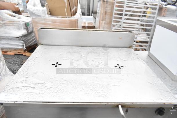 Commercial floor-style braising pan, stainless steel finish, used condition with water droplets on the surface, control knob visible.