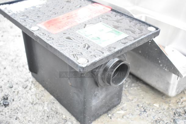BRAND NEW SCRATCH AND DENT Ashland PolyTrap 4804 grease trap, 8 lb. capacity, with threaded connections, wet with raindrops.