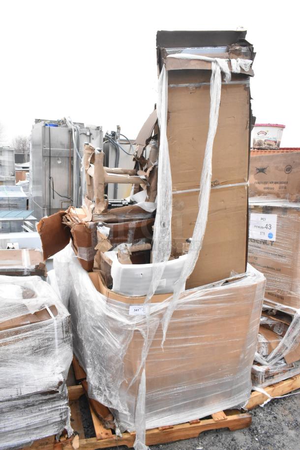 Stack of brand new scratch and dent items including a chair and sink, wrapped on a pallet, showing damaged packaging.
