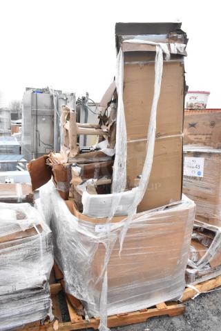 Stack of brand new scratch and dent items including a chair and sink, wrapped on a pallet, showing damaged packaging.