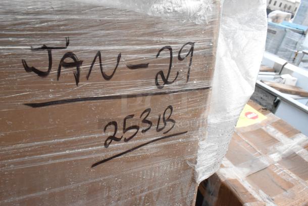 Pallet wrapped in plastic showing handwritten "JAN-29" and "253LB" markings on side of cardboard box.