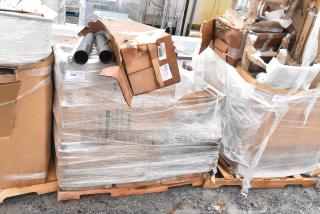 Sealed pallets with 18 new scratch and dent items, including table bases. Boxes are partially damaged. Labels and pipes visible.