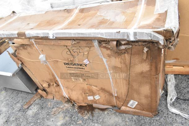 Damaged box with Regency branding; contains stainless steel work table undershelf and dish cabinet. Box shows signs of wear.
