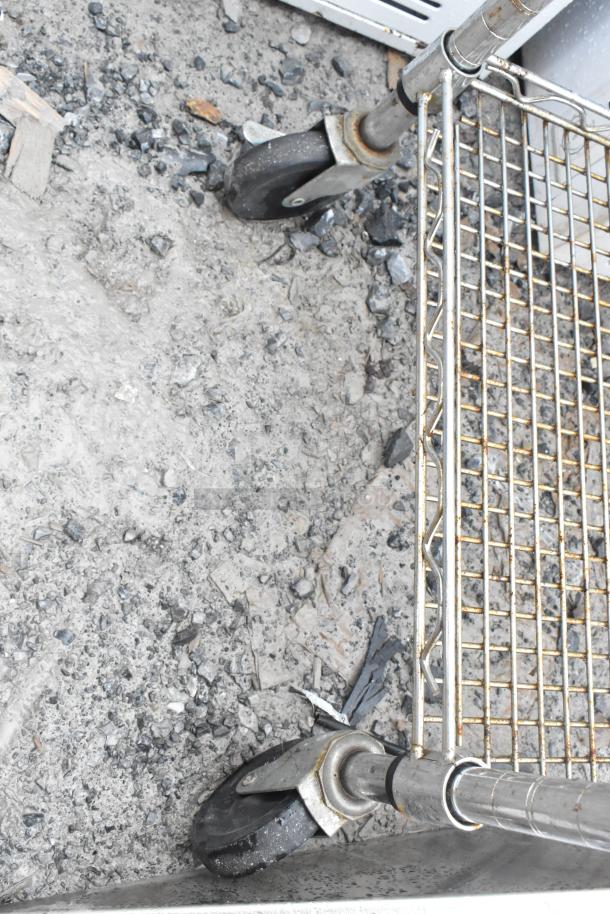 Chrome finish 3-tier wire shelf cart on commercial casters, showing rust and wear, designed for heavy-duty use.