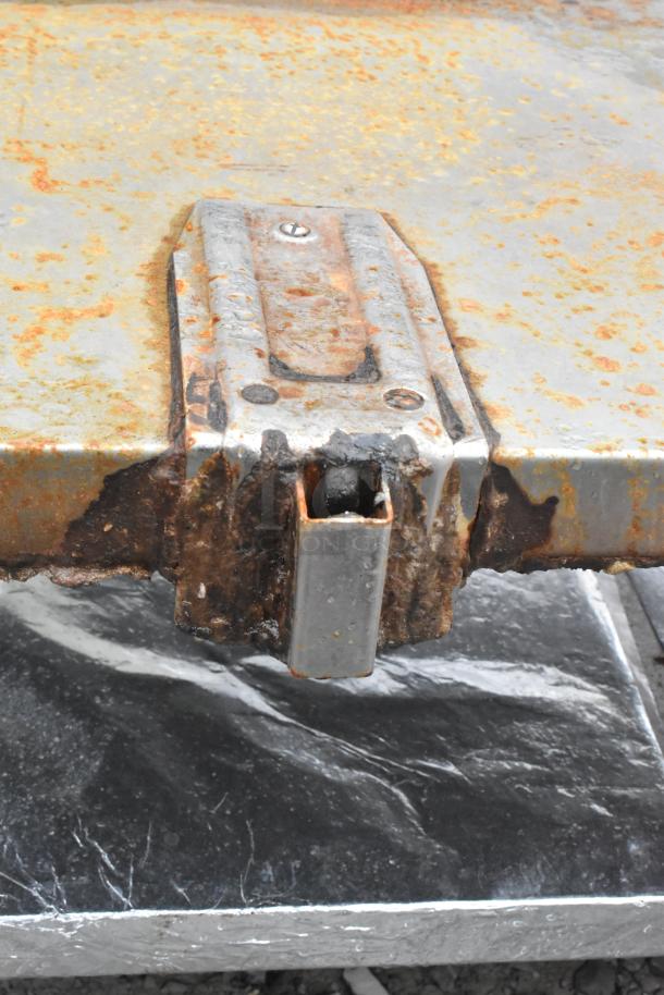 Commercial equipment stand with can opener mount, showing rust and wear. Features an under shelf for additional storage.