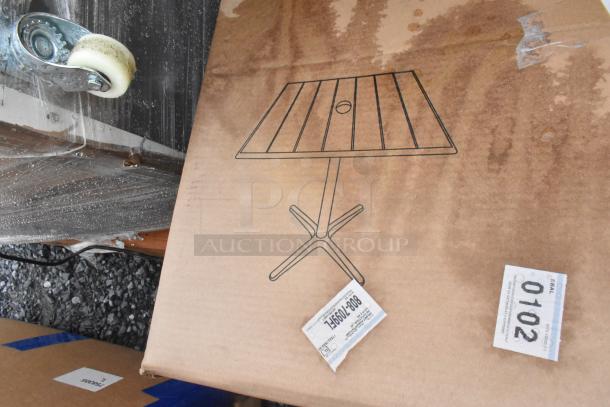 Cardboard box with outdoor table illustration, showing new scratch and dent items. Includes labels with item codes.