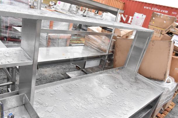 Stainless steel commercial prep station with 3-bay sink, hand sink, under shelves, and overhead shelf. Indoor use condition.