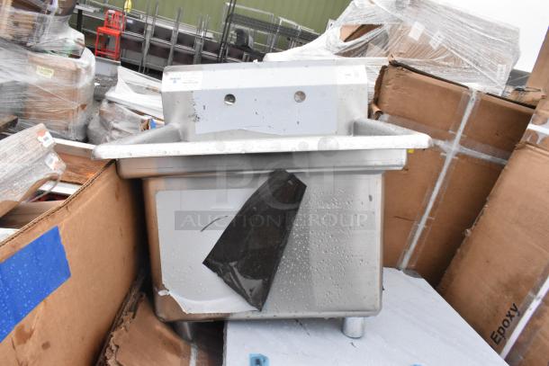 Brand new industrial stainless steel sink with minor dents, protective wrap, dual faucet holes, surrounded by packaging.
