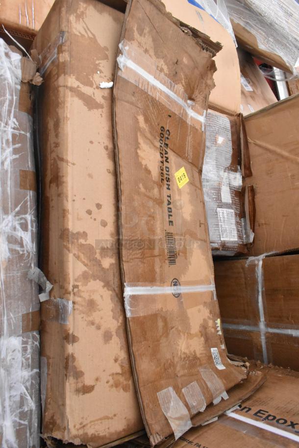 Cardboard boxes with visible labels, including "CLEAN DISH TABLE," showing signs of wear. Contains scratch and dent items, including a sink and work table.