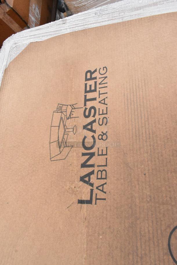 Cardboard box with "LANCASTER TABLE & SEATING" logo, containing brand new scratch and dent outdoor tables.