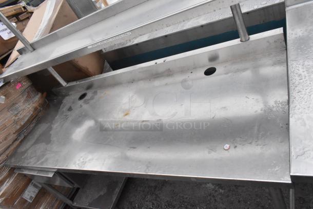Commercial stainless steel table with two-tier overshelf and drawer. Used condition, surface wear visible. Label for plates use.