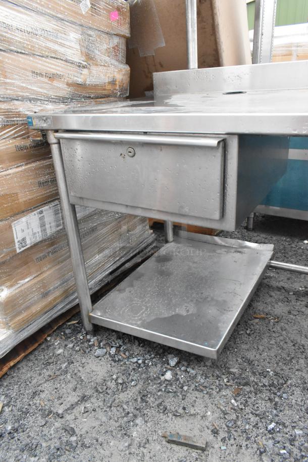 Commercial metal table with two-tier overshelf and drawer, brushed finish, used condition, sturdy construction.