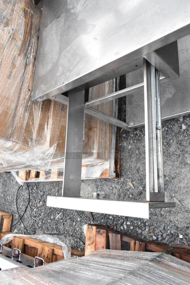 Commercial table with two-tier over shelf and drawer, stainless steel, sturdy construction, visible wear, ideal for kitchens.