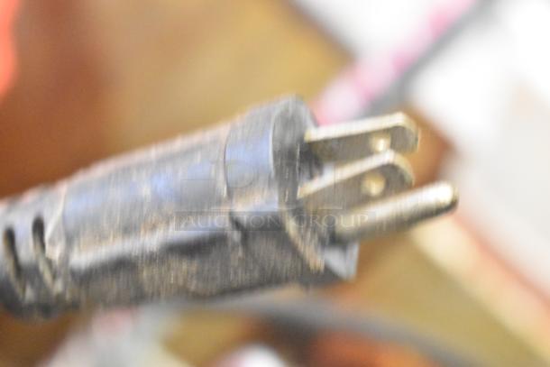 Close-up of a power plug showing the prongs and part of the cord, likely connecting to the Waring WPG250 Panini Press.