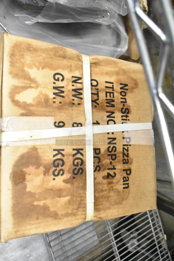 Two unopened boxes of NSP-12 non-stick pizza pans, visible markings show net weight of 8 kg and gross weight of 9 kg.