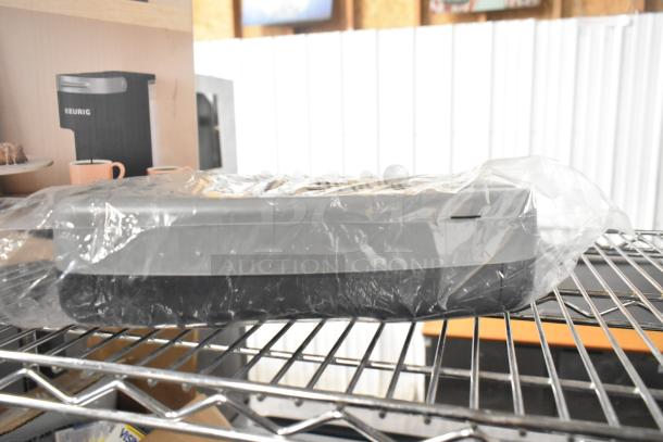 EcoPunch Electric 2-3-Hole Adjustable Punch, new in packaging, gray and black design, on storage shelf.