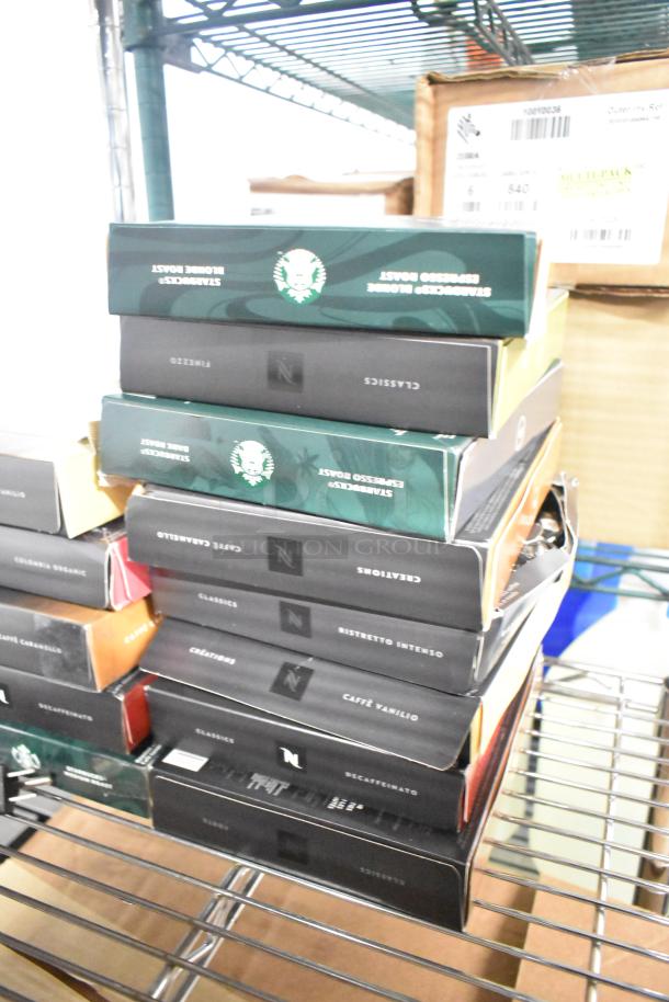 Stack of assorted coffee and beverage mix boxes, including LavAzza Vanilla Latte and Starbucks Espresso Roast, on a shelf.