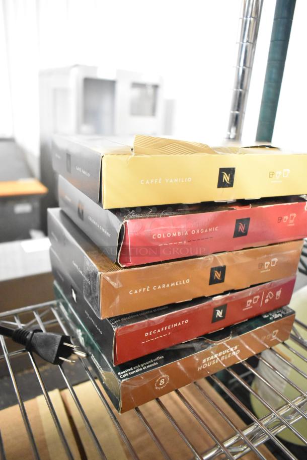 14 assorted coffee boxes including Nespresso Caffè Vanilio, Colombia Organic, Caffè Caramello, Starbucks House Blend.